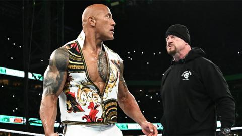 The Rock, a muscular man with tattoos looking behind him to The Undertaker, a man wearing all black.