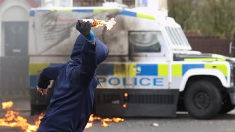 A young man throws a petrol bomb at a police Land Rover