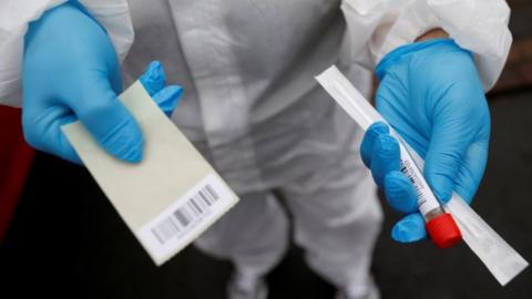 A health worker holding a coronavirus test