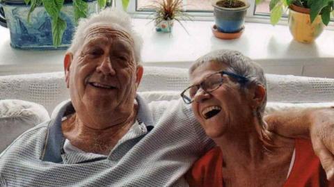 Alan and Ann Shawyer sitting on the sofa in their home
