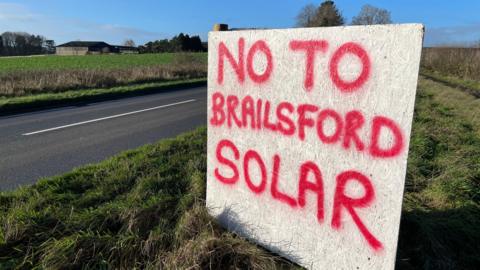 Handmade roadside sign on a wooden board which reads "No to Brailsford Solar".
