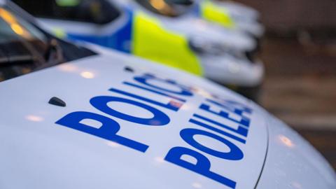 A close up image of a police van, with letters reading police close to the camera. Other police vans can be seen in the distance.