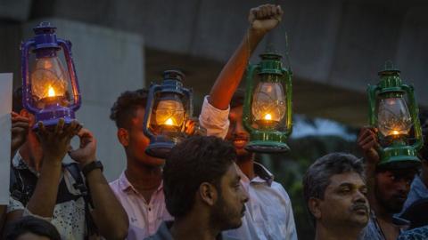 Demonstrators hold placards and oil lamps as they protest against the recent electricity crisis in Dhaka, Bangladesh on 25 July 2022.