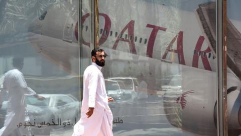 A picture taken on June 5, 2017 shows a man walking past the Qatar Airways branch in the Saudi capital Riyadh, after it had suspended all flights to Saudi Arabia following a severing of relations between major gulf states and gas-rich Qatar