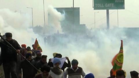 Protesting farmers running away from police tear gas in India