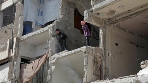 Syrian children look down from a destroyed building following air strikes on the rebel-held town of Douma, in the Eastern Ghouta (25 March 2018)