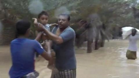 Socotra residents hand a toddler from one to another as they wade through knee-high water