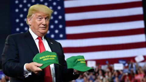 US President Donald Trump displays hats that read: "Make Our Farmers Great Again!" at a campaign rally at Ford Center in Evansville, Indiana on August 30, 2018