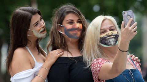 three women wearing face masks taking a photo