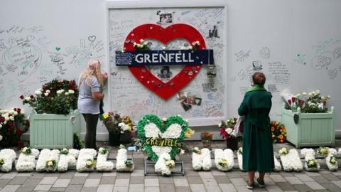 People reading tributes at hoarding