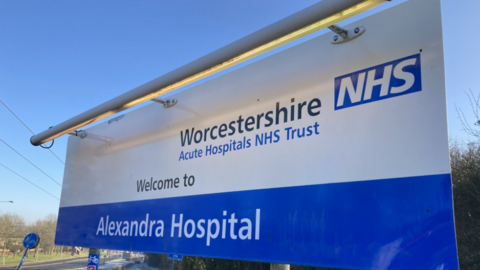 A large blue and white sign bearing the words Worcestershire Acute Hospitals NHS Trust, welcome to Alexandra Hospital