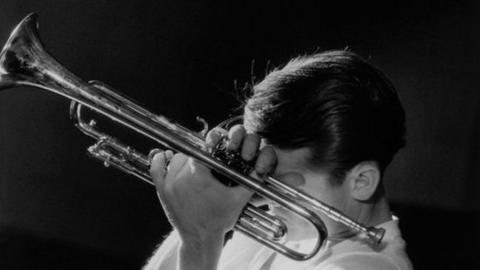 A black and white image of Chet Baker holding a trumpet in New York City in 1956.