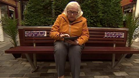 Margaret sitting on bench with tablet