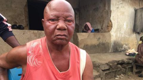 Frank Okoro sits on a chair in a red t-shirt