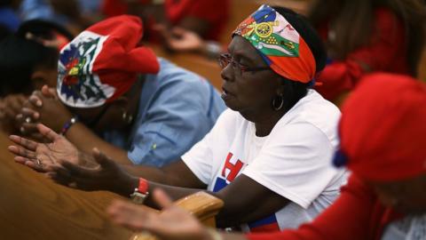 Parishioners pray together during a service at the Notre Dame D"Haiti Catholic Church as they celebrate Haitian Flag day in the Little Haiti neighborhood on May 18, 2017 in Miami, Florida.