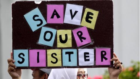 An Indonesian female activist holds a sign reading "save our sisters", in English, during a rally against sexual violence in Banda Aceh, Indonesia, on 11 May 2016