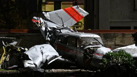 A firefighter stands next to a twin-engine Piper PA-30 Twin Comanche plane after it had to make an emergency landing in Villejuif a Parisian suburb