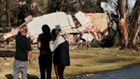 People look at a trailer home destroyed after a tornado touchdown in Mount Vernon, Alabama