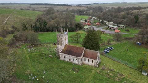 A drone image of St Giles Church with the army buildings of the former village in the background