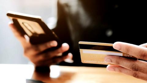 A woman holding a phone and a card