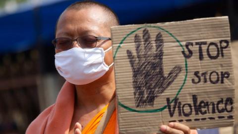 A Buddhist monk of the Dhammakaya sect temple holds a placard as monks confront with Thai policemen outside the temple in Pathum Thani, north of Bangkok, Thailand, Monday, 20 February 2017.