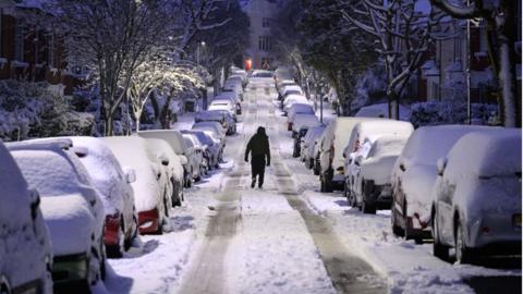 A man walks up a snow-covered road