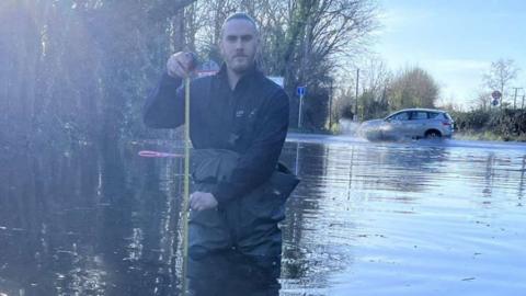 A man standing almost waist deep in floodwater