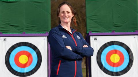 Archer Naomi Folkard poses in front of two targets after being named in Team GB's squad for Tokyo 2020