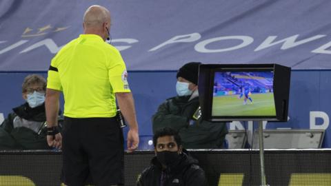 Referee Simon Hooper checks a TV monitor before awarding Fulham a penalty against Leicester