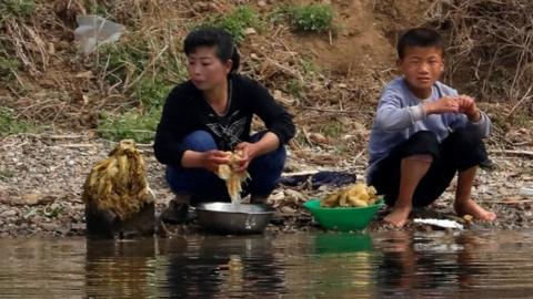 A woman and a child wash vegetables in a river in North Korea. Photo: April 2017