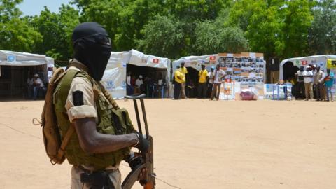 A Nigerian soldier stands guard near information stands in a camp for internally displaced people in Diffa, Niger, in 2016