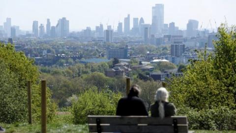 File image of a man and a woman sat on a bench in north London overlooking a view of the city skyline