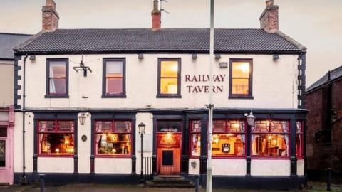 An old pub looking inviting with lights on in the windows