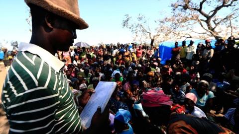 People wait to receive aid at a camp for the people displaced in the aftermath of Cyclone Idai in John Segredo near Beira, Mozambique on 31 March 2019