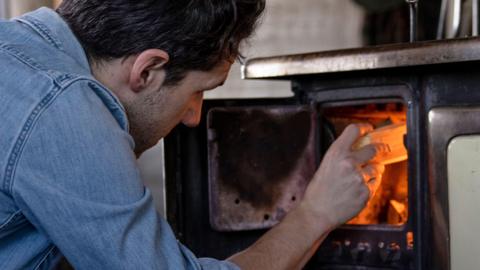 A man uses a wood burner stove