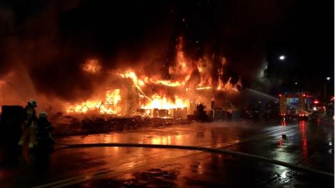 Firefighters using water cannon to extinguish a fire on a commercial and residential building in Kaohsiung city, southern Taiwan, 14 October 2021