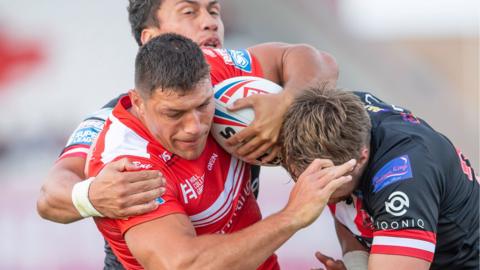 Hull KR's Ryan Hall is tackled by Salford's Elijah Taylor & Ben Davies