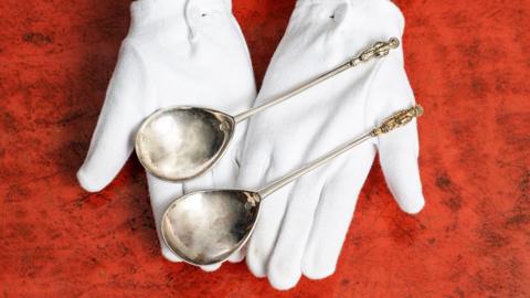 Apostle spoons being presented by gloved hands