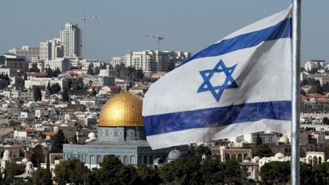 The Israeli flag flutters in front of the Dome of the Rock mosque and the city of Jerusalem, on December 1, 2017.