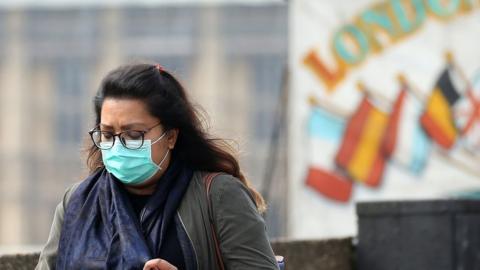 A woman wears a mask in central London