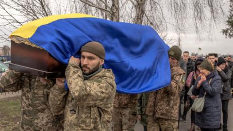 Ukrainian soldiers carry the coffin of a dead Ukrainian serviceman