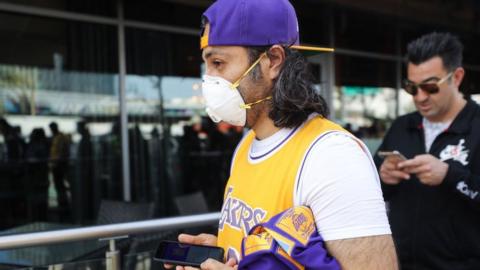 A Kobe Bryant fan wears a mask to his memorial service in LA on Monday