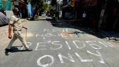 A policeman walks past a street sign by an RWA in a Delhi colony