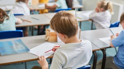 Primary school children doing schoolwork at classroom desks