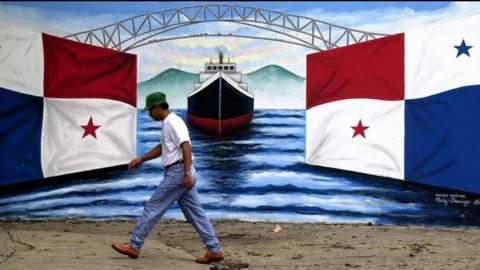 A man walks past a mural of a ship passing between two Panamanian flags Monday on 13 December 1999, in Panama City.