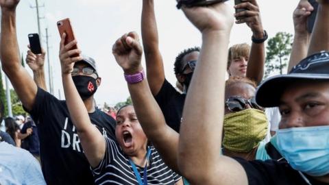 People shout and hold their phones during protests over George Floyd's death