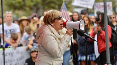 Woman with megaphone at school mask debate