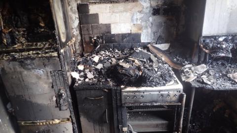 A burnt out cooker with damage to surrounding cupboards