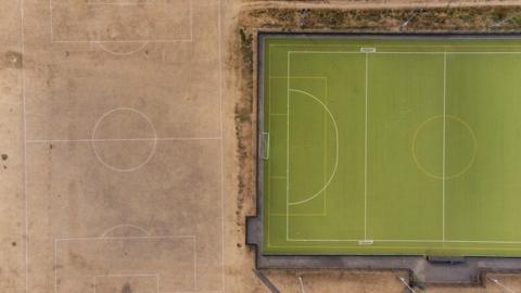 Aerial photo of an artificial pitch next to parched land