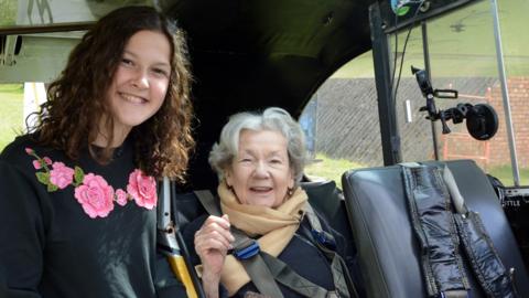 Matilda (L) stands next to the plane and her grandmother Mollie sits in the plane (R)